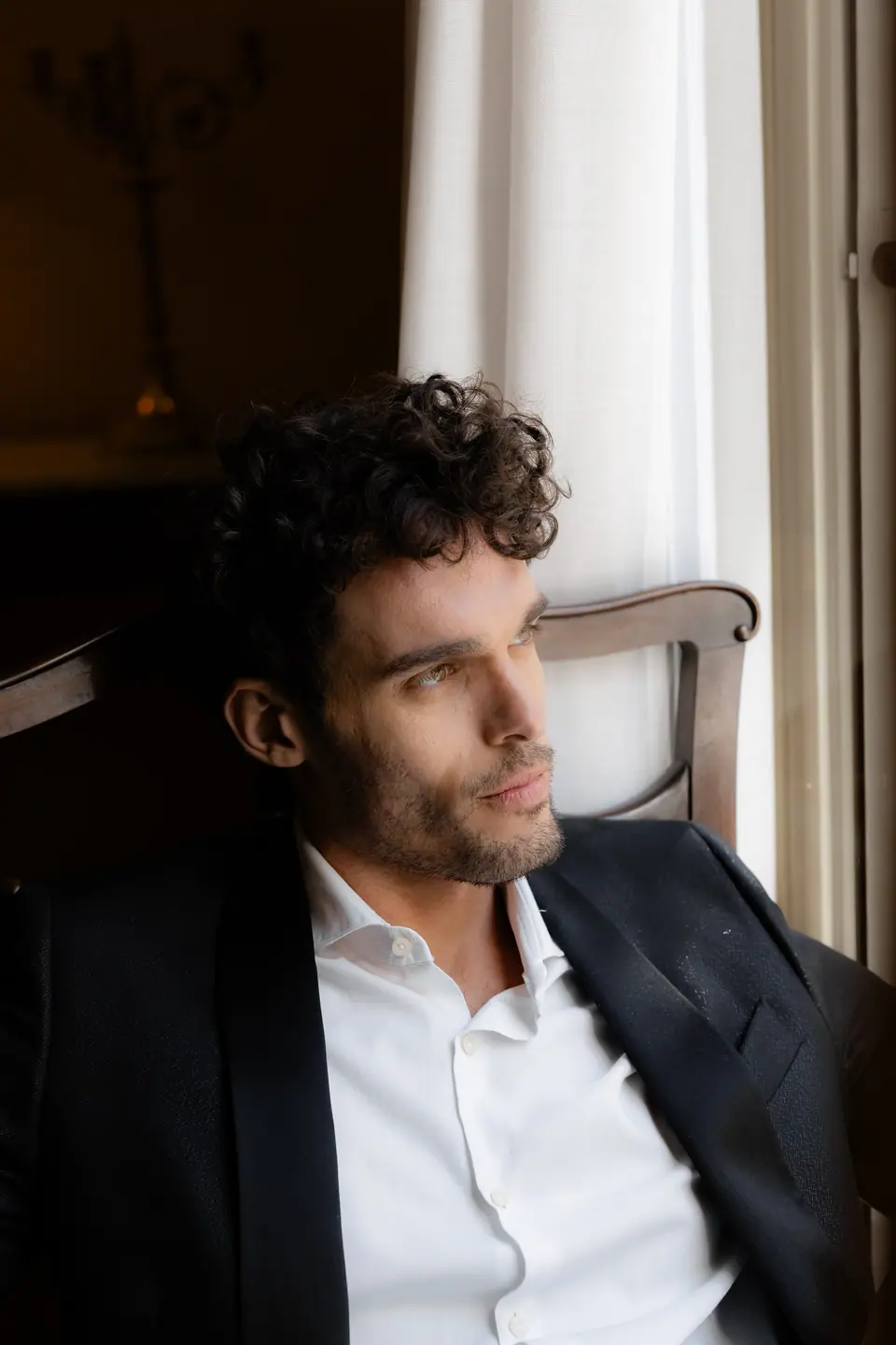 Antoine in a dinner jacket looking out of the window