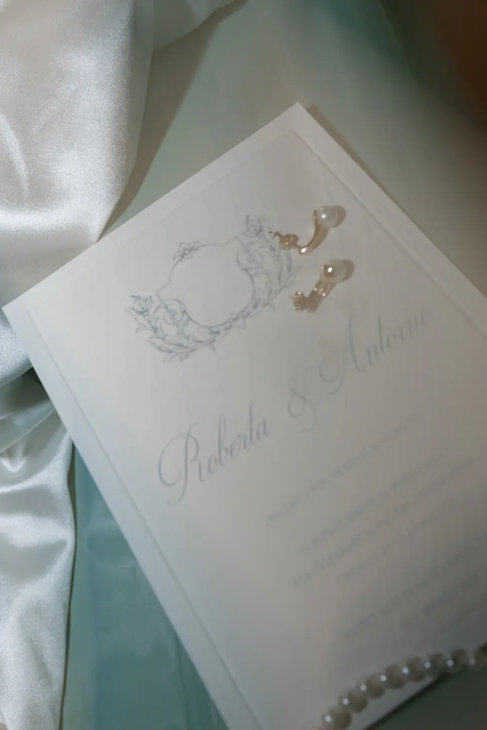 Wedding invitation for Roberta and Antoine on green satin with pearl earrings