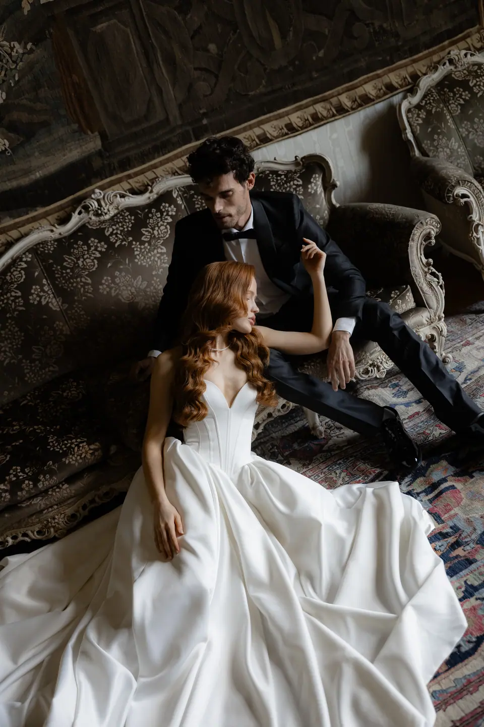 Roberta in her wedding gown on an antique sofa with Antoine behind her