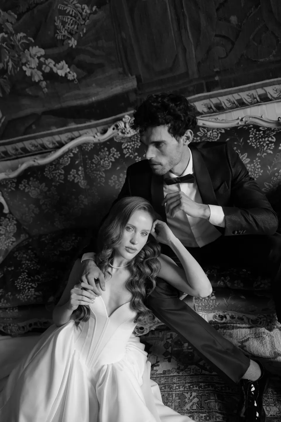 Roberta and Antoine on a sofa in black and white, her gown spread around them