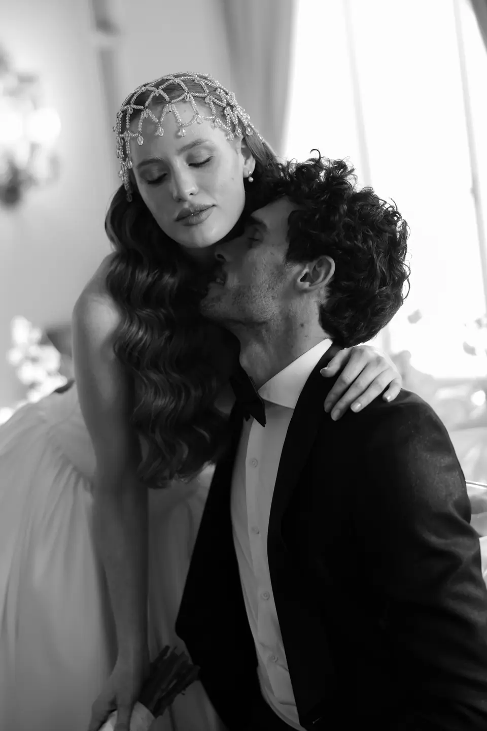 Antoine kissing Roberta’s temple as she wears a beaded headpiece, in black and white
