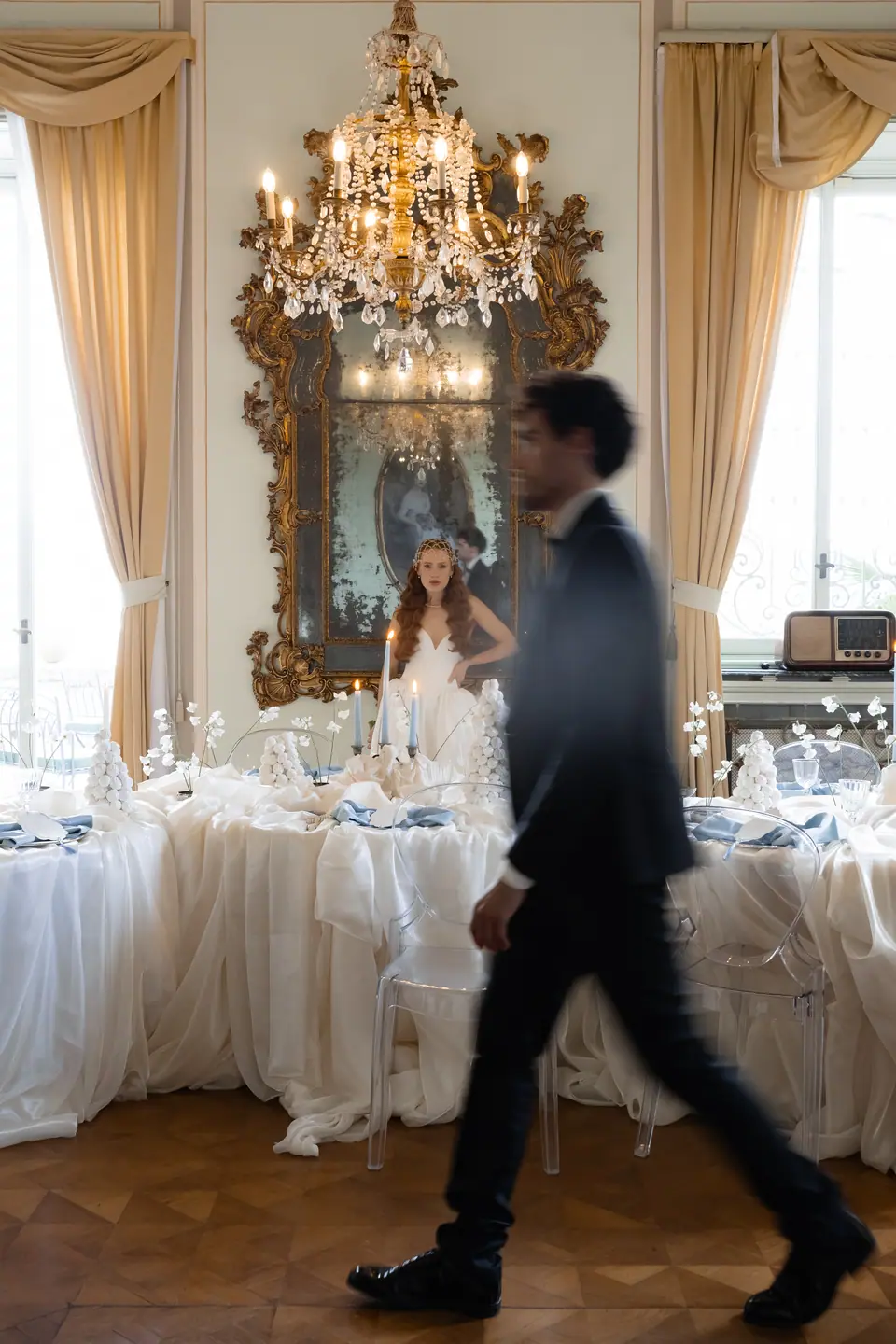 Antoine walking past a banquet table while Roberta stands in the mirror behind him