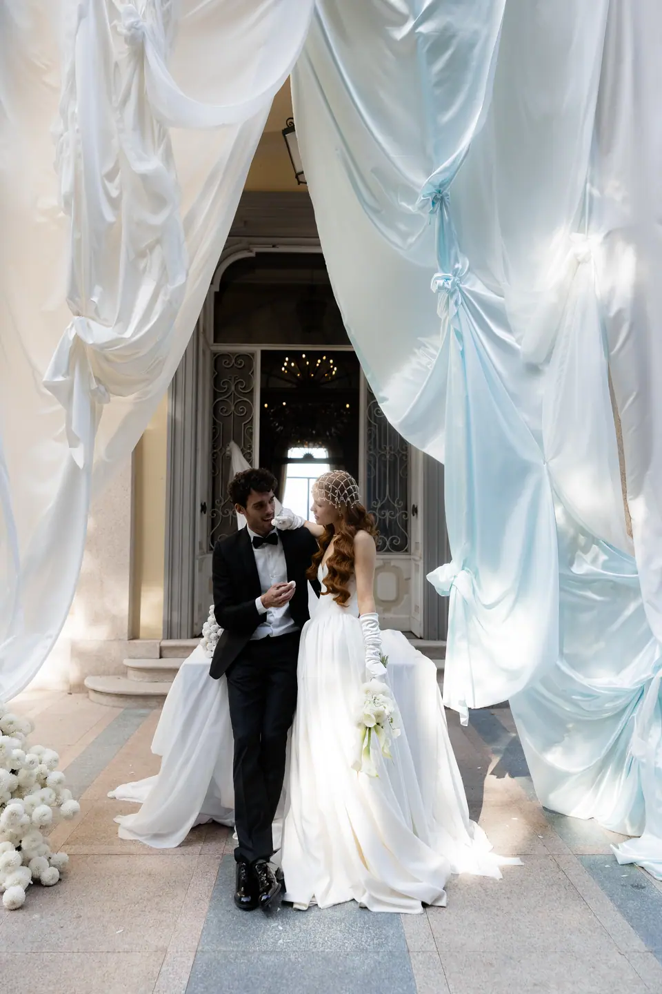 Roberta and Antoine beneath pale blue drapes at the villa entrance