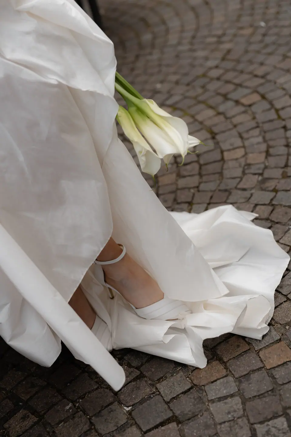 Roberta’s gown and calla lilies on the cobblestones, a satin shoe peeking out