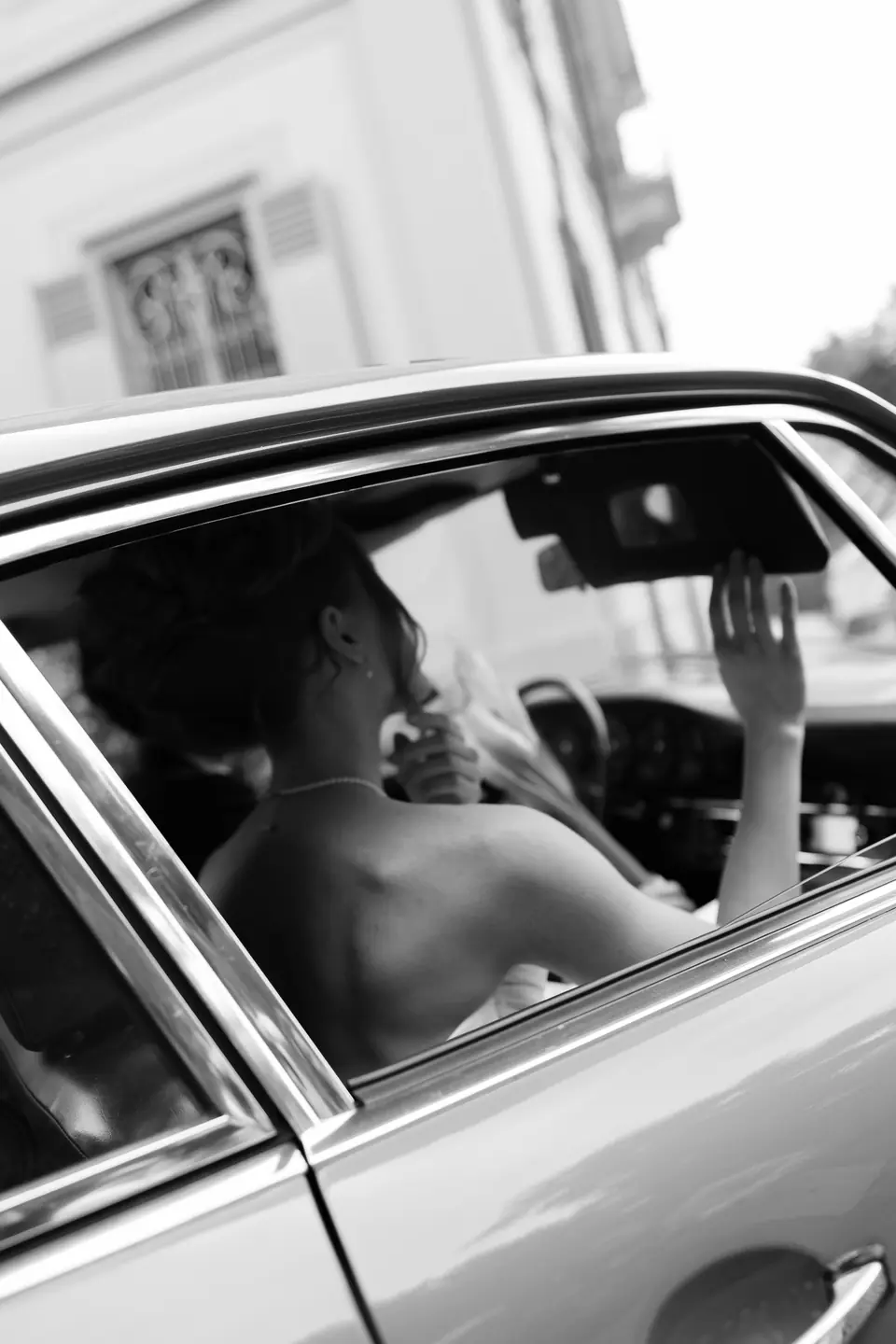 Roberta in black and white seen through a car window, her hand raised