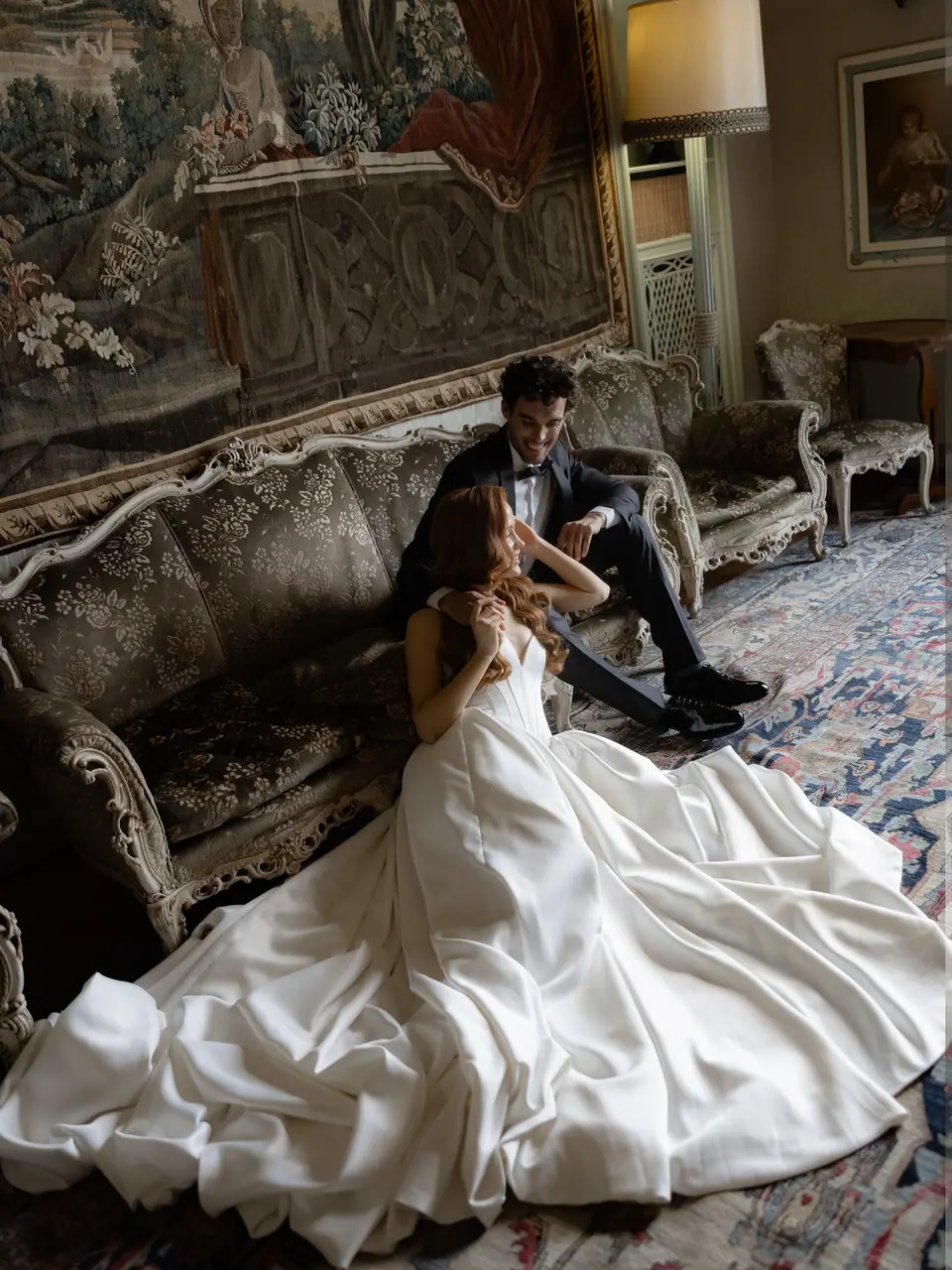 Roberta and Antoine on an antique sofa, her gown spreading over the rug