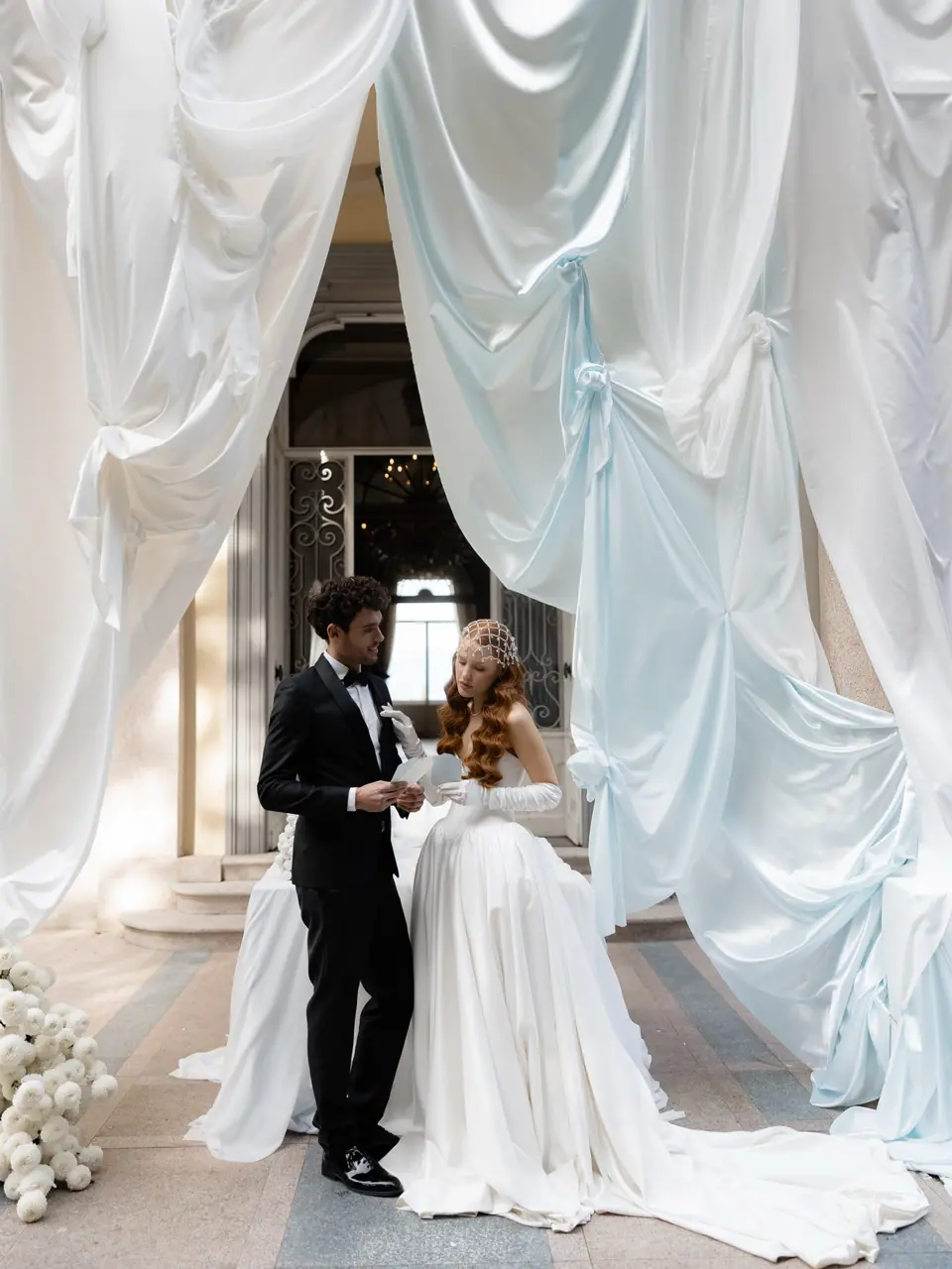 Antoine and Roberta reading beneath white and pale blue drapes